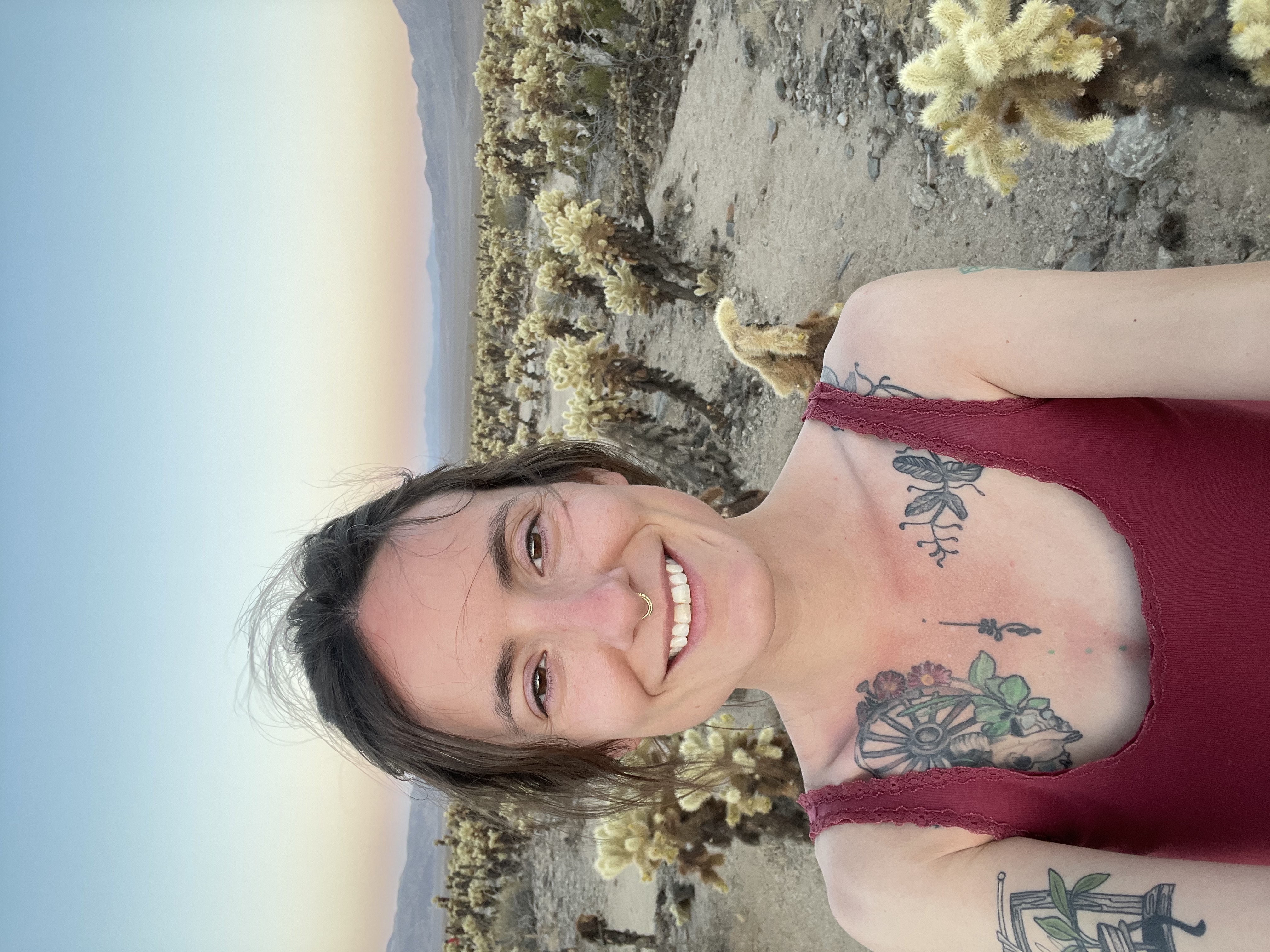 Meg smiling outdoors in the desert near a cholla cactus